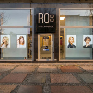 Zdjęcie stacjonarnego salonu peruk Rokoko w Szczecinie, w którym na witrynie i półkach wyeksponowane są peruki naturalne i syntetyczne.