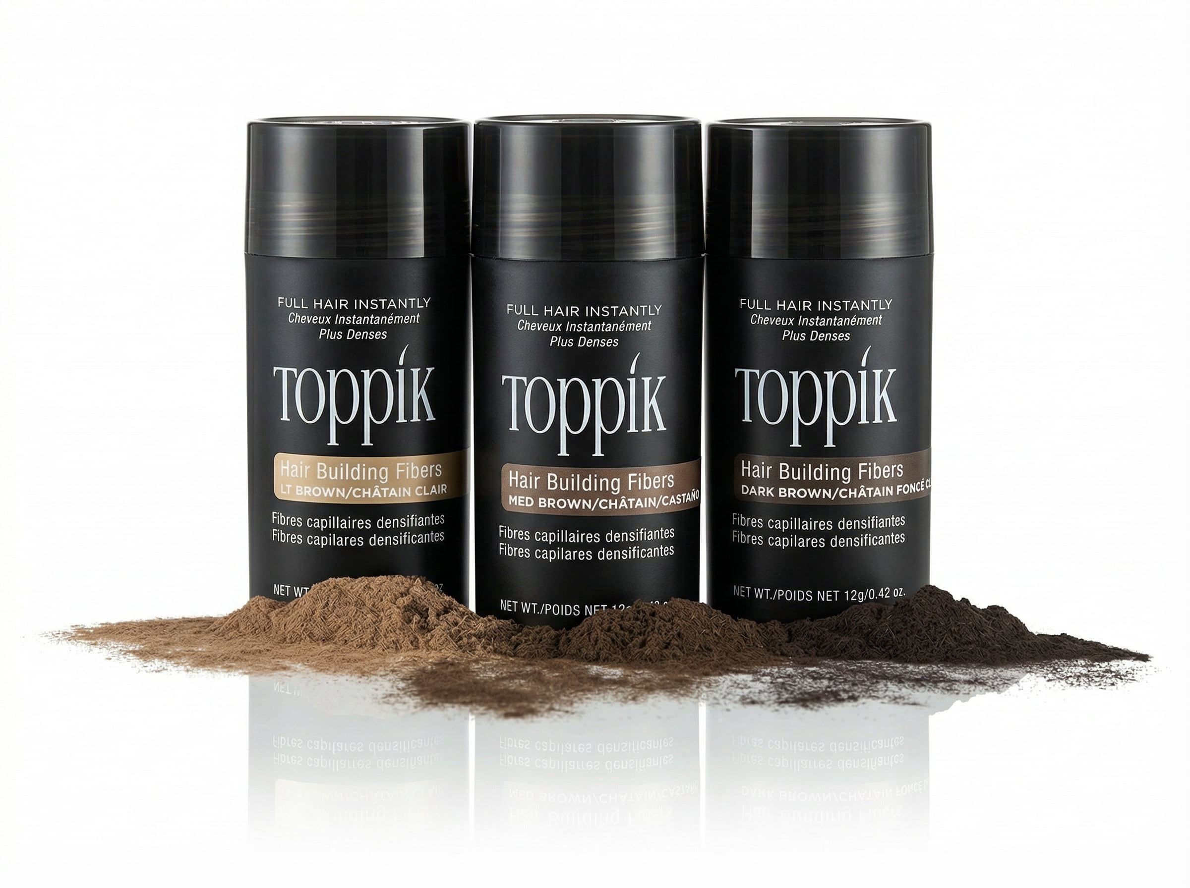 Trzy czarne opakowania Toppik stojące na&nbsp;białym tle z&nbsp;wysypanymi obok włóknami zagęszczającymi w&nbsp;różnych odcieniach.